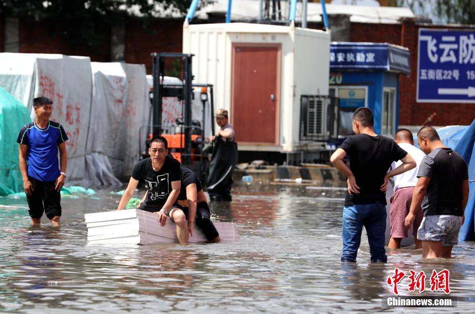 哈尔滨暴雨后多地内涝 市民划自制“竹筏”抢救财物