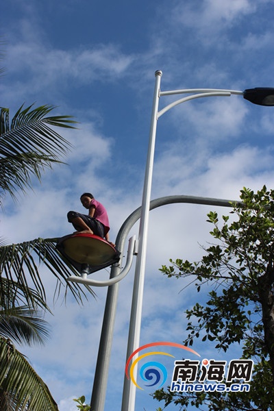 组图:女子爬上三亚湾9米高电线杆 腾跳自如拒救助
