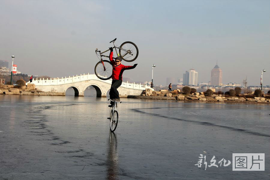 长春：车王冰面站立举单车骑行